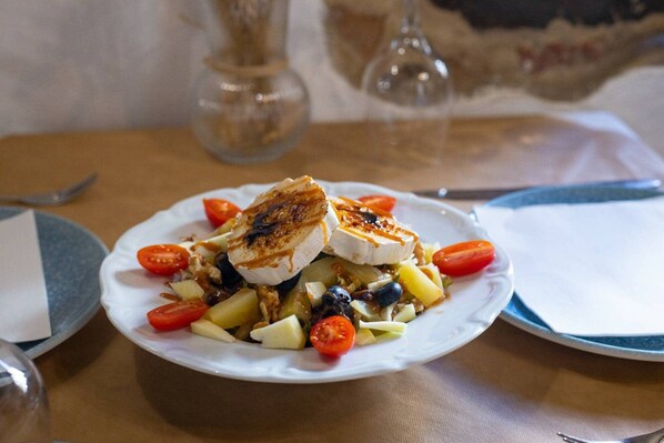 Une assiette de nourriture comprenant du poulet grillé, des légumes et une sauce, posée sur une table.