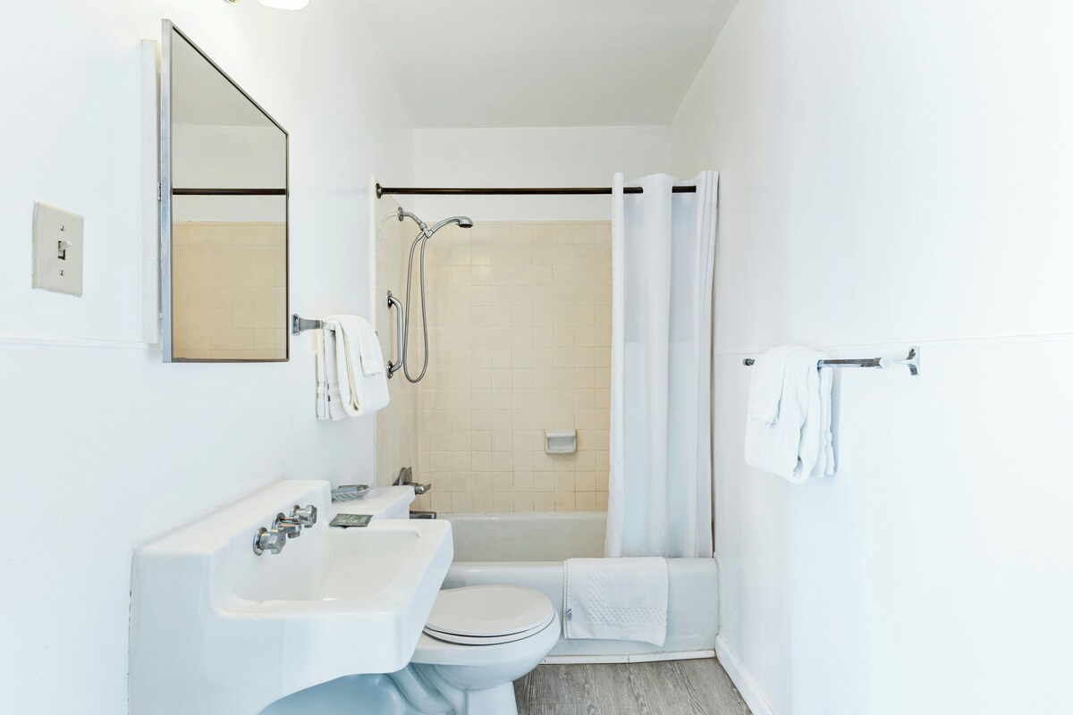 A bathroom with a white sink, toilet, and shower area.