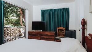 A bedroom with a bed, a dresser, a chair, a TV, and a window with curtains. - Royal Grove Waikiki (Honolulu)