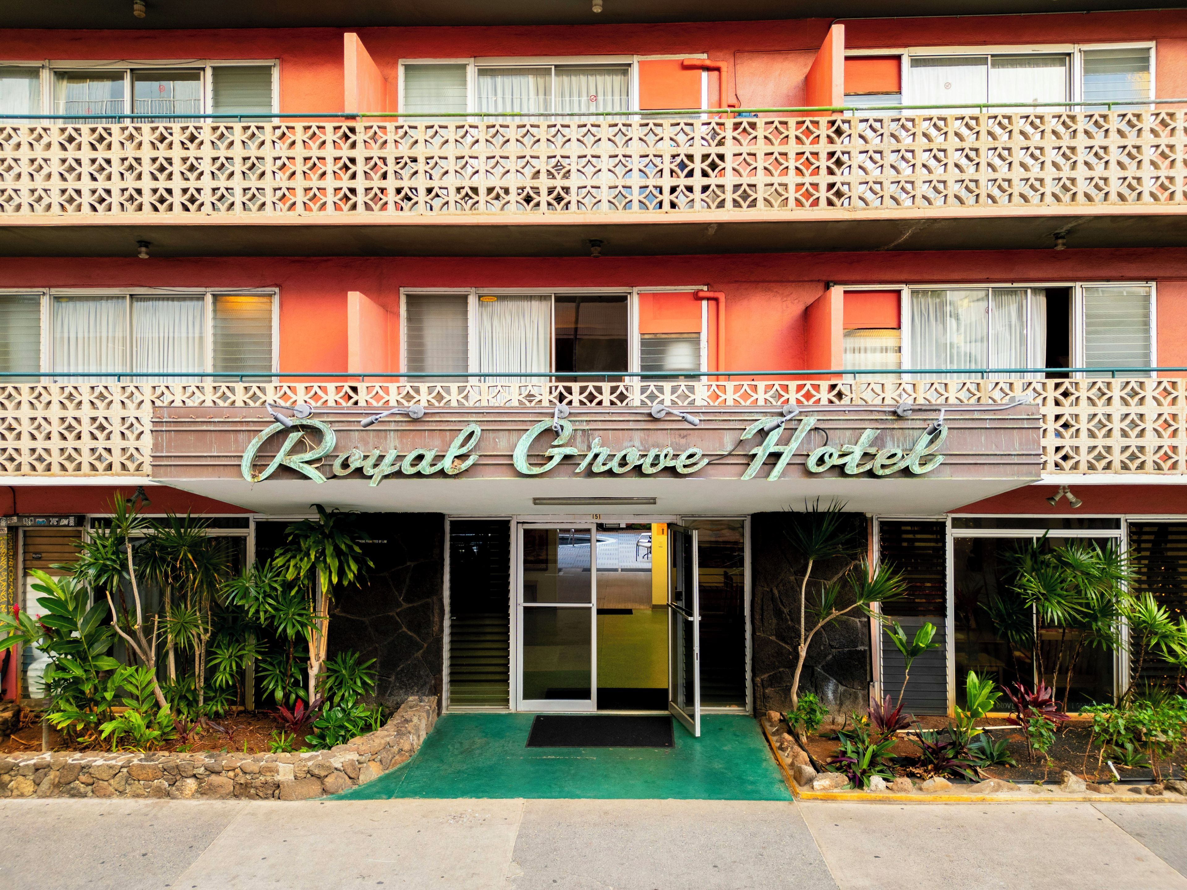 Ein Hotel mit einem Schild, das 'Royal Grove Hotel' zeigt, und einem Balkon mit Gitterwerk.
