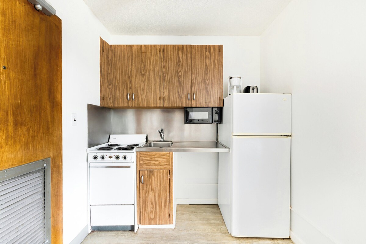 A compact kitchen with wooden cabinets, a white stove, a sink, and a refrigerator.