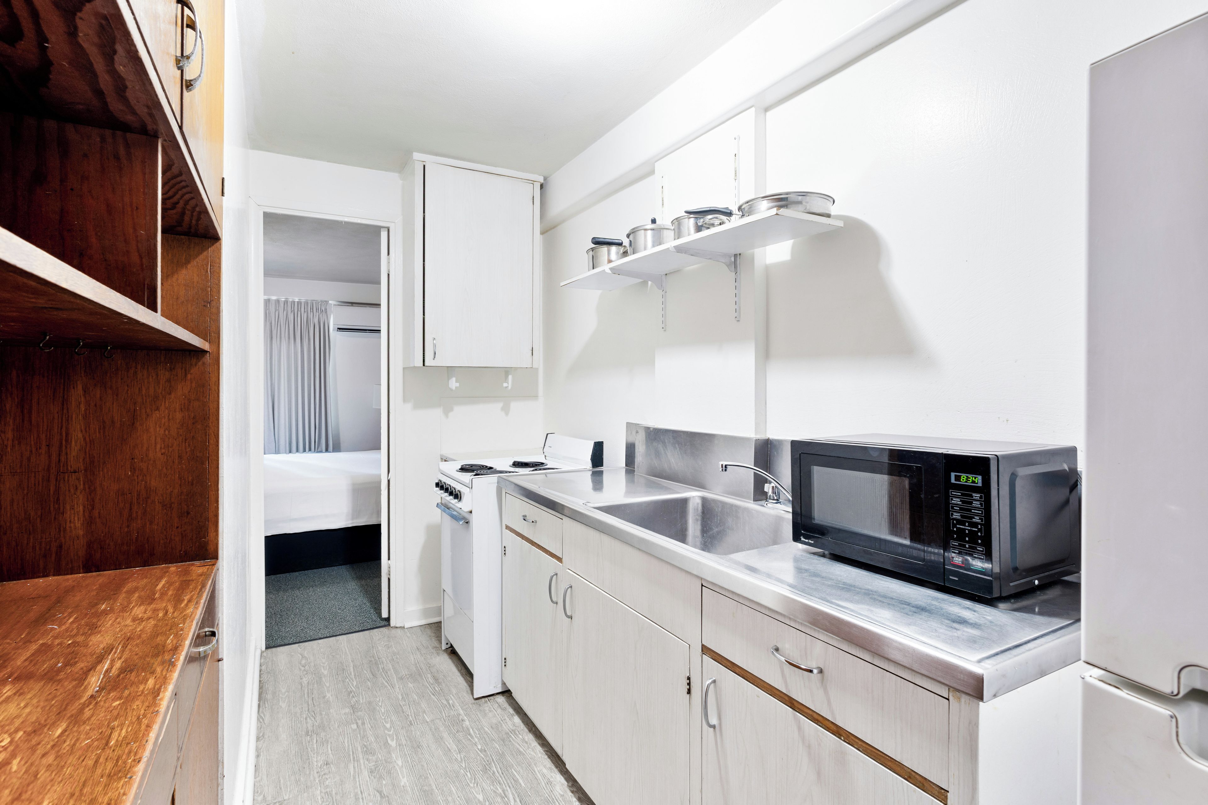 A compact kitchenette with a stove, microwave, and sink.