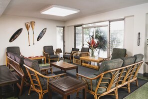 A room with wicker furniture, a wooden coffee table, and a large window with blinds. - Royal Grove Waikiki (Honolulu)