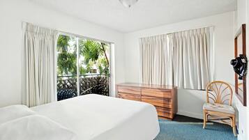 Una habitación de hotel con una cama, un tocador de madera, una silla y una ventana con cortinas.