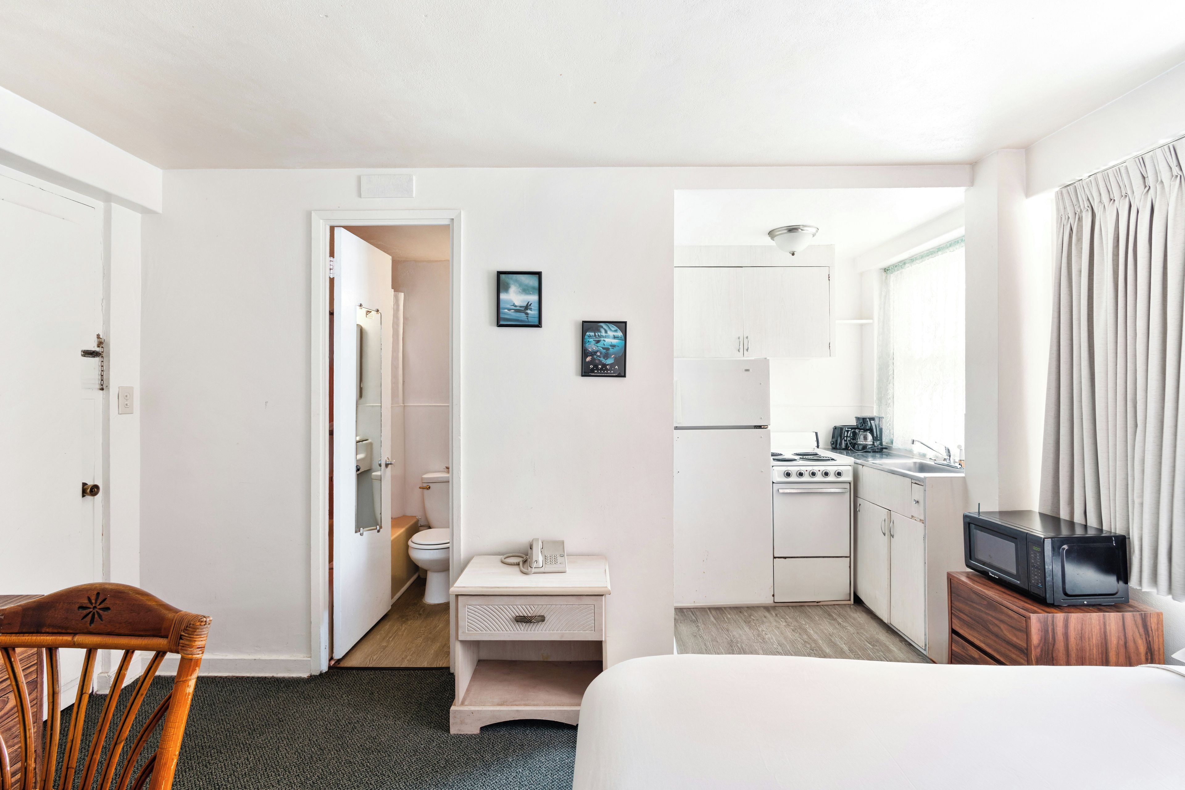 Habitación de hotel compacta con kitchenette, una pequeña zona de comedor, cama y baño.