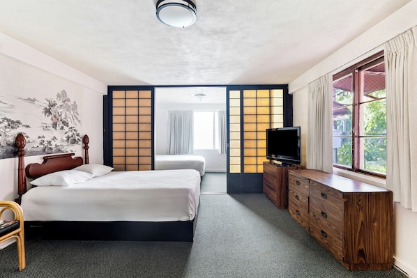 A hotel room with a bed, a TV, a dresser, and a window with curtains. - Royal Grove Waikiki (Honolulu)