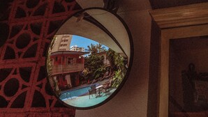 A circular mirror reflecting a pool area with lounge chairs and a building in the background. - Royal Grove Waikiki (Honolulu)