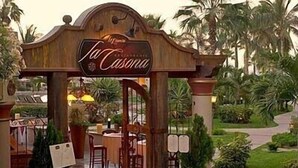 Un arco de madera en la entrada con el nombre "La Casona" y un letrero que indica un restaurante.