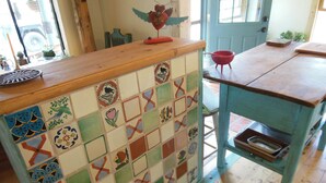A kitchen with a tiled backsplash, wooden counter, and a blue table with a tray. -  Casita Juliet in Taos, New Mexico (Taos)