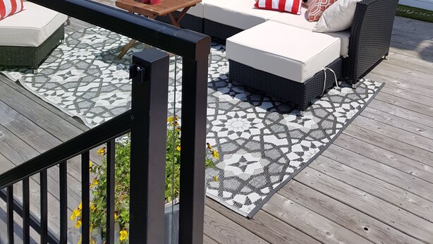 Une terrasse dotée de mobilier d’extérieur, d’un barbecue et d’un espace patio agrémenté d’un tapis à motifs.