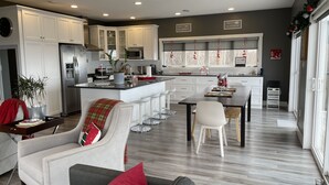 Une cuisine moderne avec des meubles blancs, un îlot central et un coin repas avec des chaises blanches.