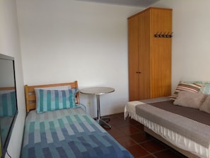 A small, neatly arranged bedroom with a bed, a small round table, a wardrobe, and a mirror. - HOUSE IN THE MIDDLE OF NATURE (Florianopolis)