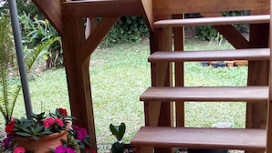 A wooden staircase leading to a covered outdoor area with potted plants and a bench. - HOUSE IN THE MIDDLE OF NATURE (Florianopolis)
