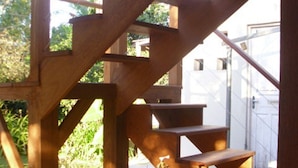 A wooden staircase with a terracotta pot with plants at the bottom. - HOUSE IN THE MIDDLE OF NATURE (Florianopolis)