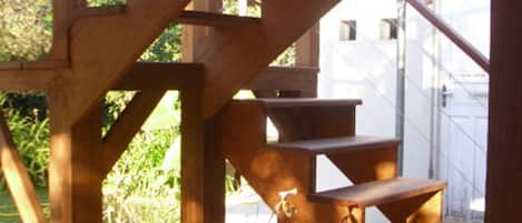 A wooden staircase with a terracotta pot with plants at the bottom.