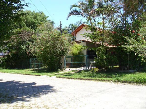 A house with a tiled roof, surrounded by lush greenery and a paved driveway. - HOUSE IN THE MIDDLE OF NATURE (Florianopolis)