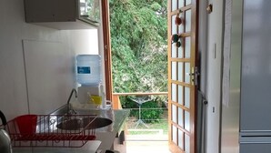 A kitchen with a stove, sink, and a view of the outdoors through a door. - HOUSE IN THE MIDDLE OF NATURE (Florianopolis)