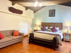 Un dormitorio con una cama, un sofá y una mesita de noche con lámparas.