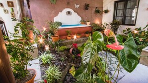 Un jardín interior acogedor con diversas plantas en macetas y una pequeña fuente.