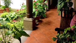 A covered outdoor area with potted plants and a bench. - Hotel La Galeria (Antigua Guatemala)