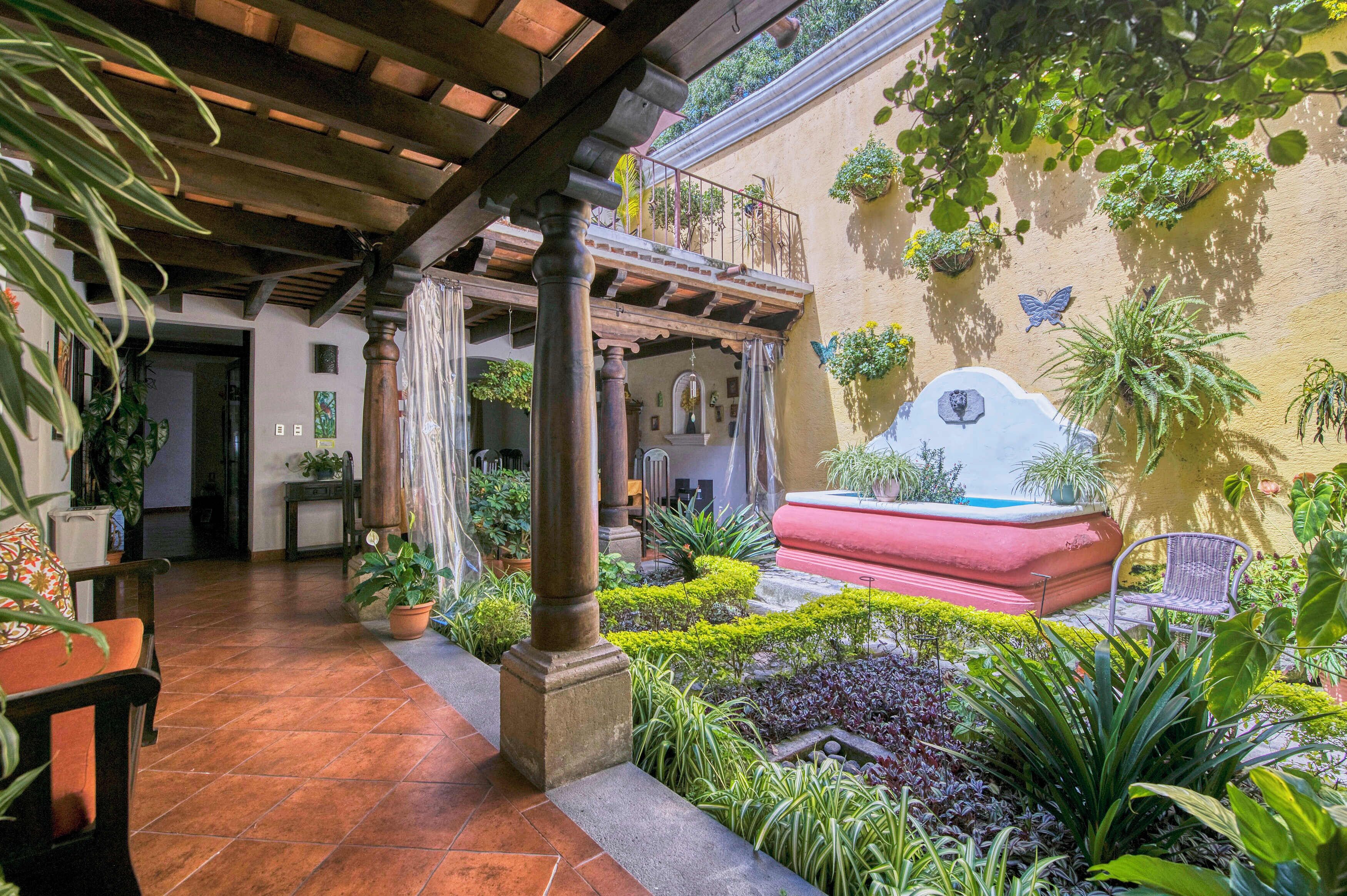 A courtyard with a fountain, potted plants, and a seating area.