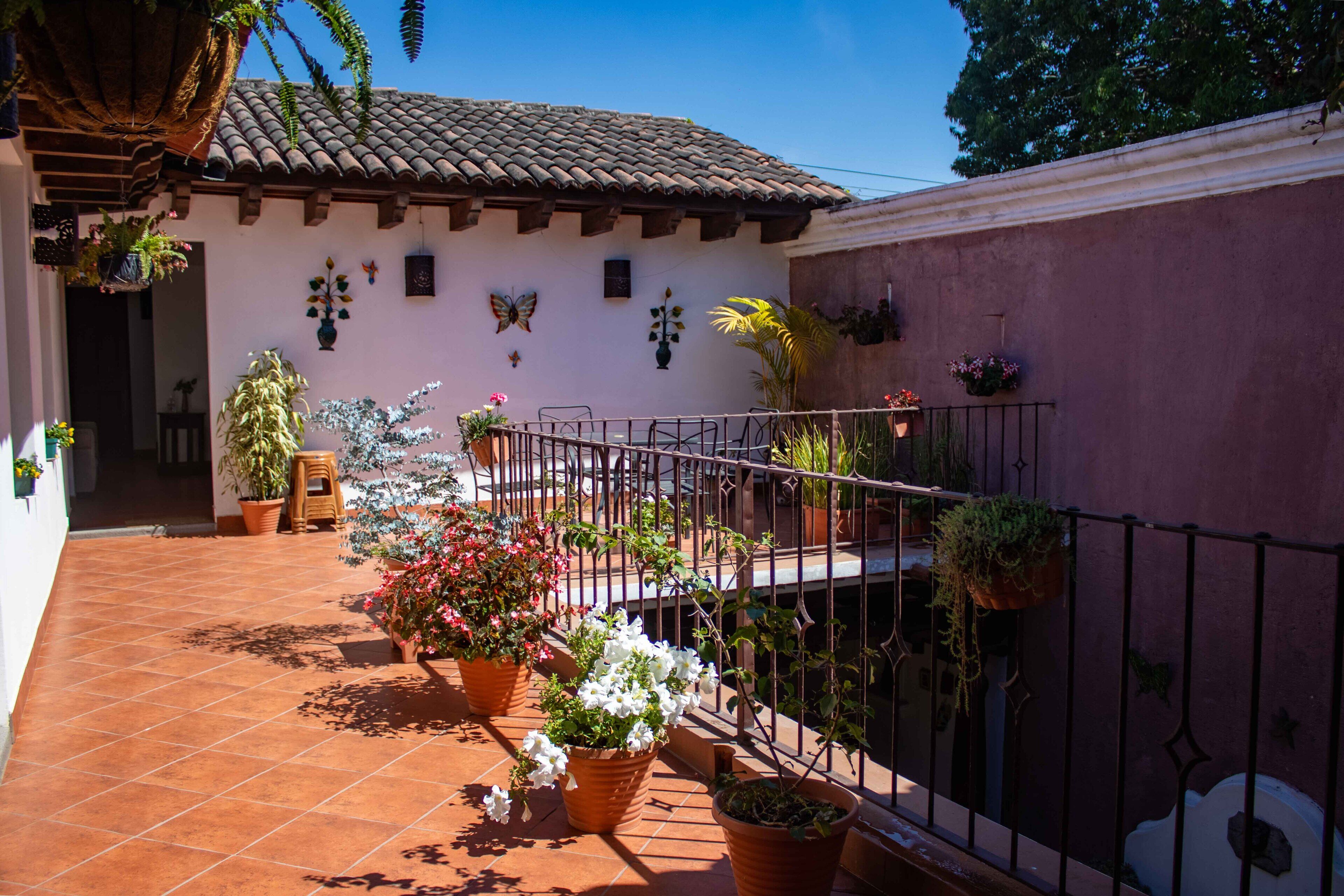 A courtyard with a tiled floor, potted plants, and a building with a tiled roof.