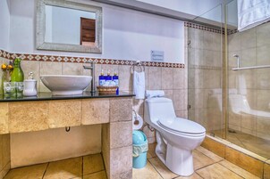 Baño con lavamanos, inodoro y zona de ducha.