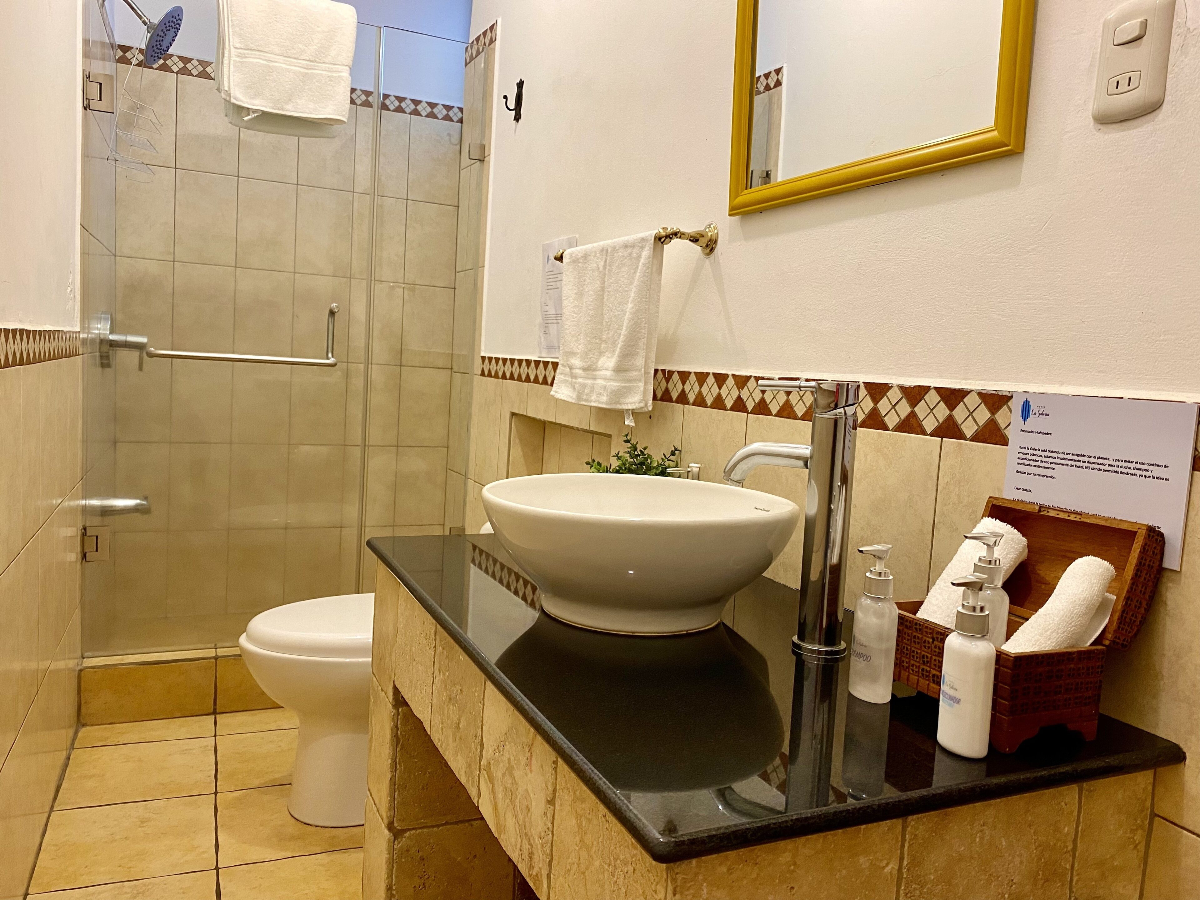 A bathroom with a glass-enclosed shower, a white sink, and a vanity with toiletries.