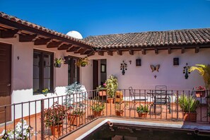 Un patio con piscina, plantas en macetas y mobiliario de exterior.