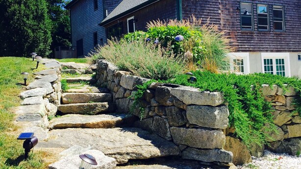 Un escalier en pierre mène à une maison en bois dotée d’un toit en pente.