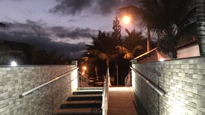 Escadaria com paredes azulejadas e corrimãos de metal, levando à entrada de um edifício.