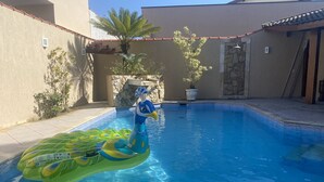 Piscina com brinquedos infláveis e plantas em vasos.