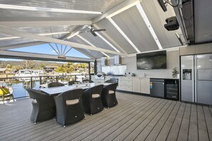 A modern kitchen with a large island, dining area with wicker chairs, and a view of a marina.