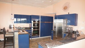 Een moderne keuken met blauwe kastjes, roestvrijstalen apparatuur en een granieten aanrecht.