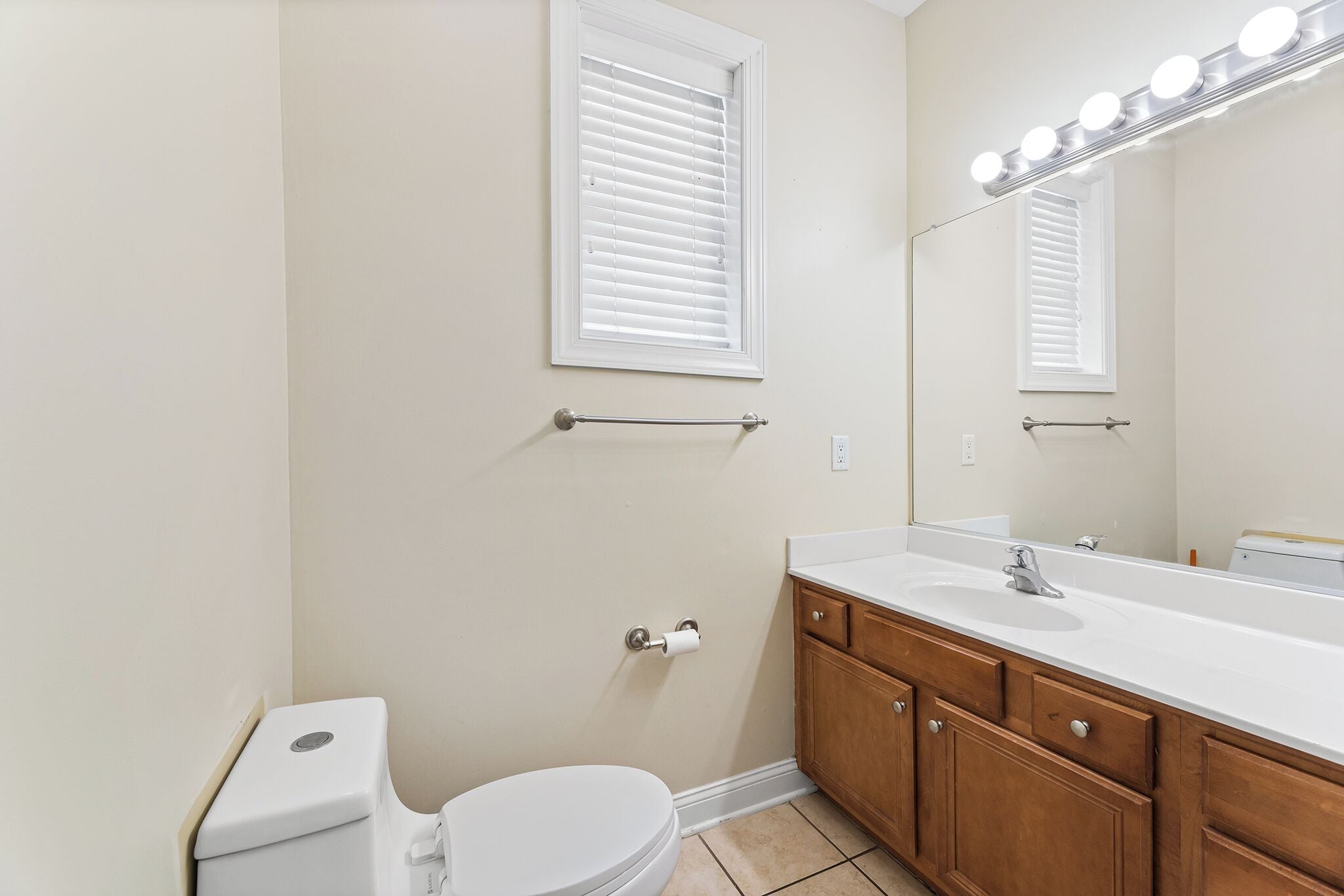 Une salle de bain comprenant des toilettes, un lavabo, un meuble-lavabo et un miroir avec éclairage.
