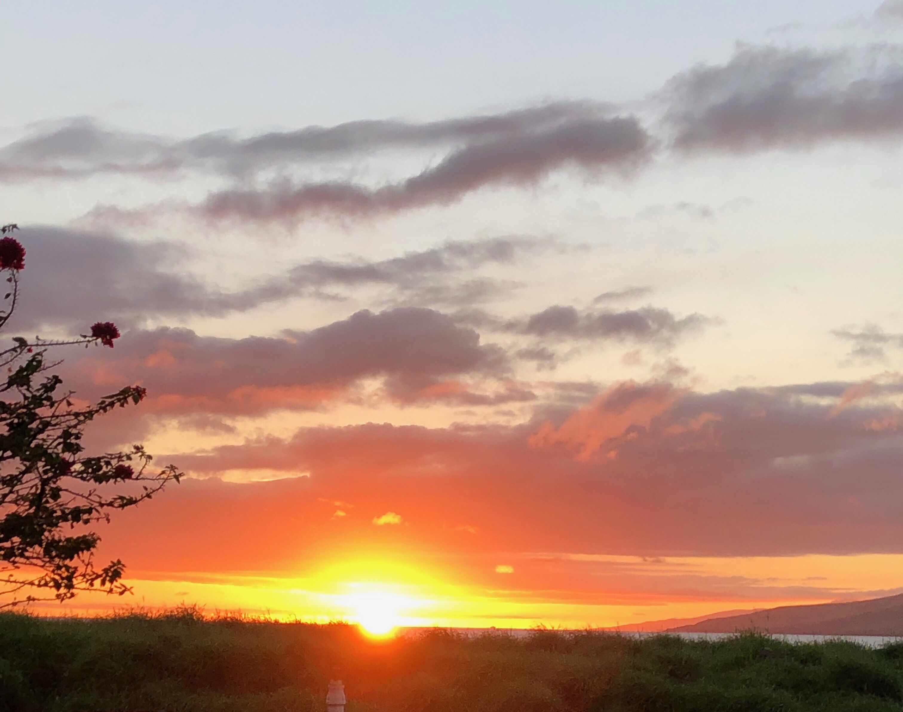 A sunset over a body of water with a distant mountain range.