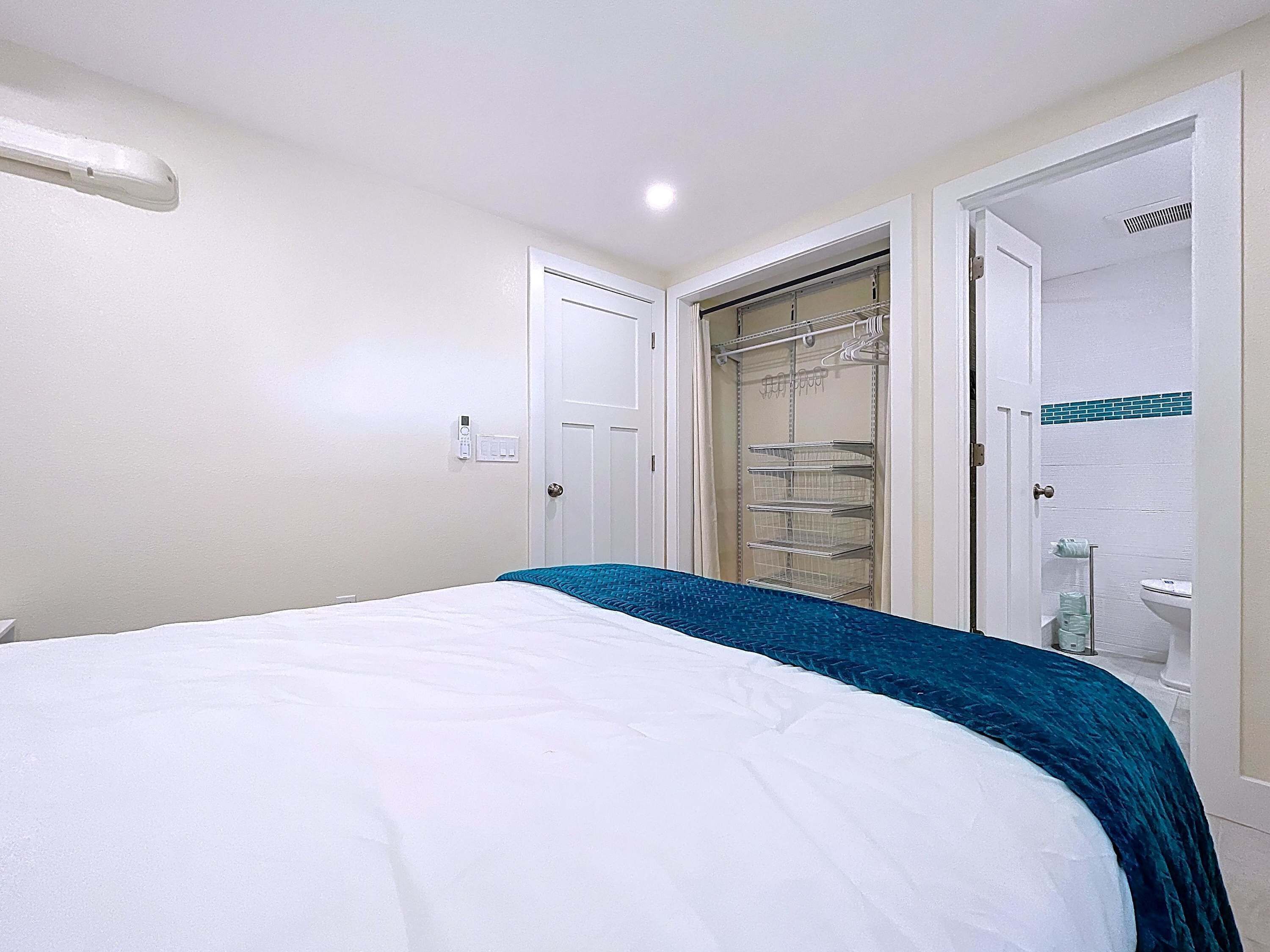 A hotel room with a bed, a wardrobe, and a bathroom.