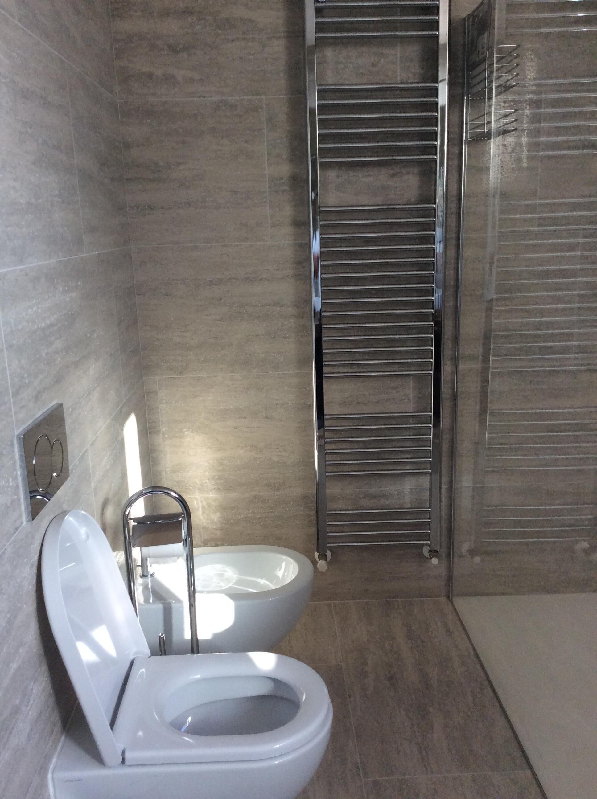 A modern bathroom with a toilet, a bidet, and a towel rack.