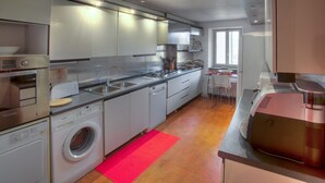 Ett modernt kök med rostfria vitvaror, en inbyggd ugn och en tvättmaskin.