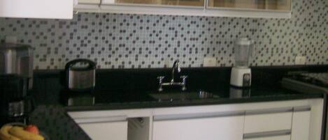 A kitchen with white cabinets, a black countertop, a sink, and a window above the countertop.