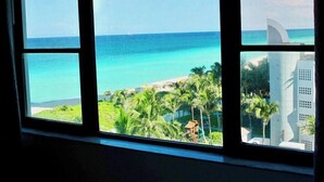 A window with a view of a beach and a building with a unique architectural design.