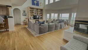 Un salon spacieux avec un grand canapé d’angle, une cheminée et une vue sur l’océan.