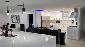 Een moderne keuken met een groot eiland, witte kasten en een roestvrijstalen koelkast.