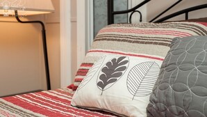 Un lit avec une literie à rayures et des coussins décoratifs, une lampe de chevet et un cadre de lit en métal.