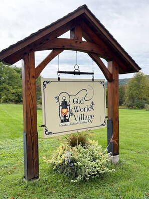 Een houten bord met een lantaarn en de tekst 'Old World Village', dat een vakantieverblijf en trouwlocatie aangeeft.