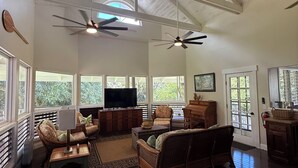 Un vaste salon doté de hauts plafonds, de grandes fenêtres et d’un ventilateur de plafond.
