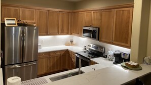 A modern kitchen with wooden cabinets, stainless steel appliances, and a marble countertop.