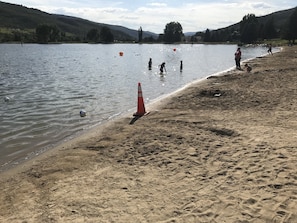 Una playa arenosa con una masa de agua, un cono de tráfico y algunas personas.
