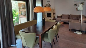 A modern living room with a dining area, featuring a stone fireplace, a sofa set, and a dining table with chairs. - Peaceful house with lots of privacy near Umag. Sea view. (Buje)
