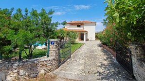 A pathway leading to a two-story house with a tiled roof, surrounded by greenery and a stone wall. - Peaceful house with lots of privacy near Umag. Sea view. (Buje)